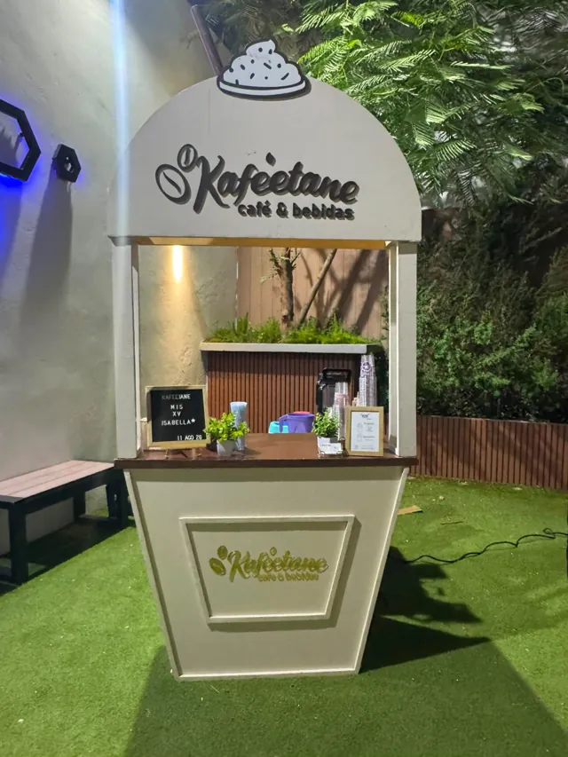 Carrito de bebidas montado en un jardín con pasto y plantas