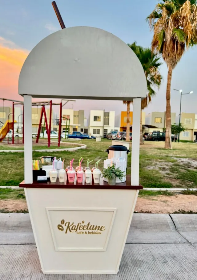 Carrito de bebidas con smoothies rosas al atardecer en un parque